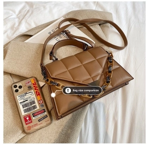 Detailed view of brown quilted bag with V-shaped metal hardware and chain strap