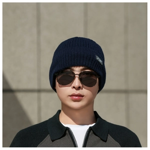 Detail of navy blue ribbed knit beanie with a FUMY woven label in outdoor winter setting