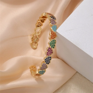 Detailed close-up of gold-plated open bangle with colorful heart-shaped cubic zirconia stones