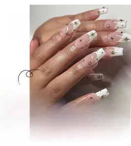 Detail of French tip press-on nails with golden starburst charms and silver dots