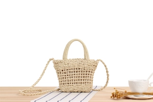 Detail of beige paper rope woven bag with hollow mesh texture on a wooden table