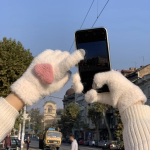 Winter touch screen plush gloves with pink heart pattern used on a smartphone outdoors