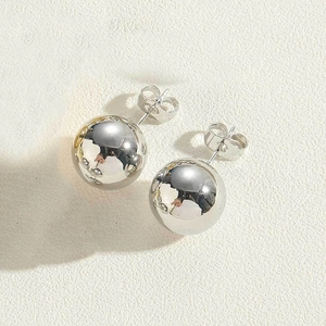Macro view of minimalist polished silver sphere stud earrings with smooth mirror finish