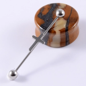 Close-up of silver stainless steel industrial barbell with cross design on stone stand