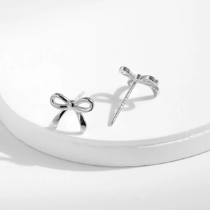 Elegant S925 sterling silver bow knot stud earrings on a professional white stand