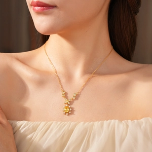 Nahaufnahme einer Vintage-Goldkette mit gelbem Edelsteinanhänger an einem Modell