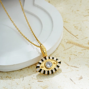 Macro shot of 18K gold evil eye pendant with white zircon and black-white enamel detail