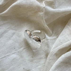 Macro detail of a 925 sterling silver heart ring with a polished fluid metal finish