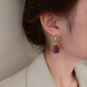 Detailed close-up of a vintage purple pearl and diamond drop earring worn by a model