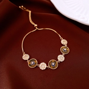 Detail of 18k gold plated bracelet featuring tiger eye eye-charms and starburst motifs