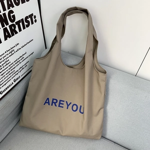 Close-up of khaki canvas tote bag with blue lettering resting on a modern grey sofa