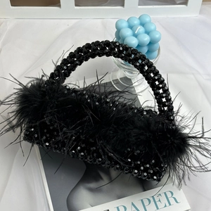 Detailed view of luxury black beaded handbag with soft ostrich feathers on magazine