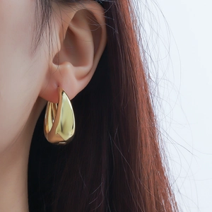 Minimalist gold teardrop earrings in polished 925 sterling silver worn by a model