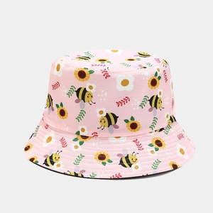 Close-up of pink bucket hat featuring cute cartoon bee and sunflower prints on cotton