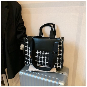 Detail of black and white houndstooth tote bag on silver suitcase for business travel