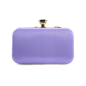 Detailed front view of purple satin evening clutch bag with gold rhinestone flower clasp