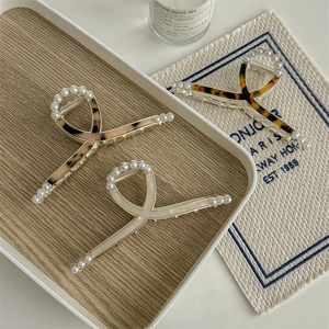 Three-piece acetate pearl hair claw clips with leopard and amber patterns in a tray