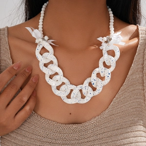 Close-up of chunky white resin chain necklace with blue ink spots and a white ribbon bow