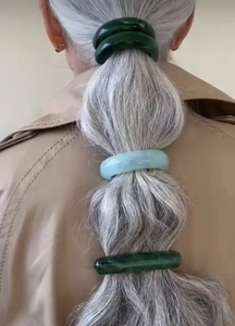 Detail of three high-elastic resin hair rings in dark and light green on a ponytail