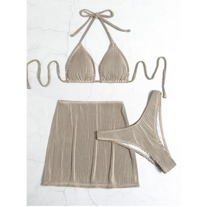 Flat lay of three-piece beige bikini set with textured ribbed fabric and matching skirt