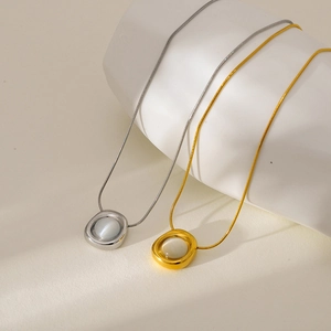 Gold and silver snake chain necklaces with marble stone pendants on ceramic