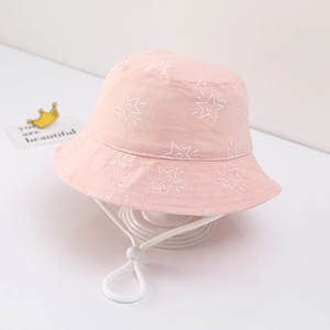 Detailed view of pink cotton baby bucket hat featuring white star print and adjustable strap.