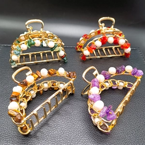 Detailed view of curved metal hair claws set with natural crystal chips and pearls