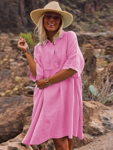Detail of pink linen polo dress showing texture and button-up front in outdoor sunlight