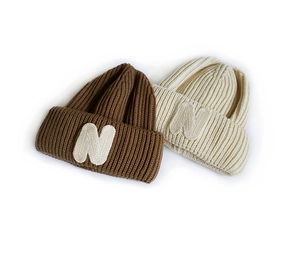 Detailed close-up of brown and beige knitted beanies with embroidered N letter patch