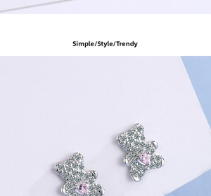 Macro shot of silver bear stud earrings with pink heart gemstone and sparkling cubic zirconia