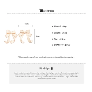 Detailed view of cream bow earrings showing alloy material and silver needle specs