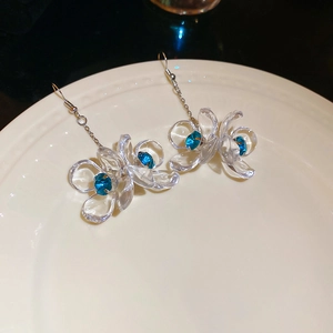 Detail of silver drop earrings with transparent acrylic flowers and blue rhinestones
