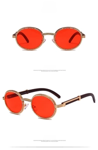 Close-up of vintage gold round frames with red lenses and diamond chain details