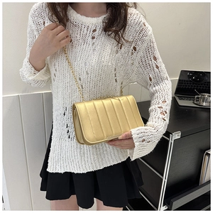 Detail of a chic golden chain bag with vertical stitching shown in a fashion lifestyle setting