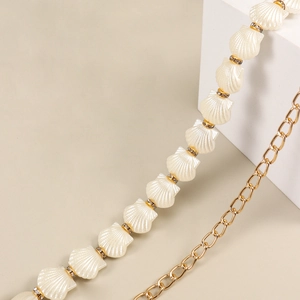Detailed shot of gold metal waist chain with shell-shaped beads and sparkling rhinestones