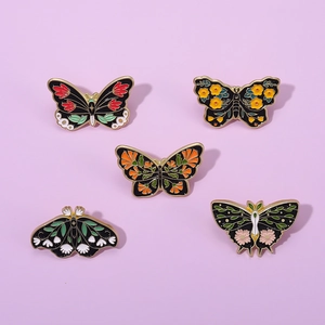 Set of five vintage enamel butterfly pins with floral patterns on a lavender backdrop
