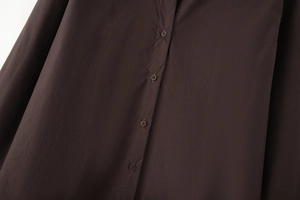 Detail of dark brown poplin shirt featuring a button placket and smooth fabric texture