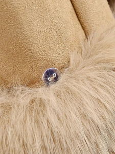 Macro detail of khaki faux suede fabric with faux fur trim and a transparent button