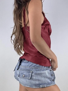 Detail view of burgundy satin camisole top paired with distressed denim shorts