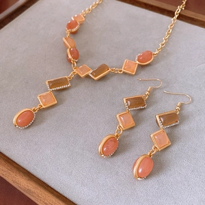 Primo piano di collana e orecchini vintage con pietre geometriche color pesca