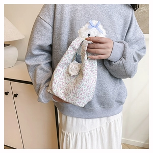 Floral print handbag with white plush bunny charm and blue bow on a fabric material