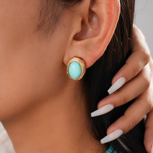 Macro shot of bohemian turquoise stud earrings with textured gold scalloped edges on ear