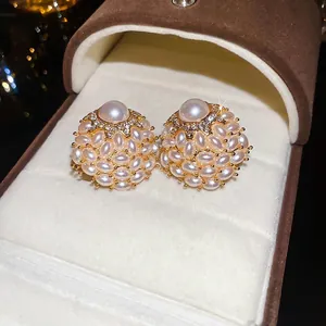 Elegant gold flower cluster earrings with faux pearls and rhinestones on brown velvet