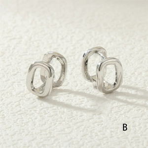 Detail of silver-toned horseshoe buckle earrings with polished mirror finish and chain link