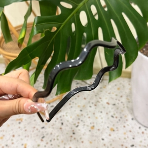 Minimalist black wavy acetate headband with glossy finish for women's hair styling