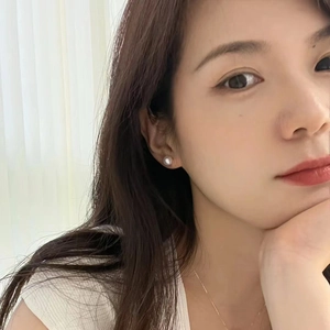 Close-up of elegant white freshwater pearl earrings on model with gold necklace
