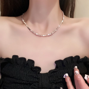 Detail of silver-tone irregular nugget necklace worn on neck with elegant luster