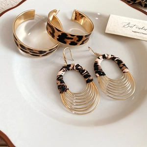 Detailed macro view of vintage leopard print leather oval multilayer earrings on ceramic tray