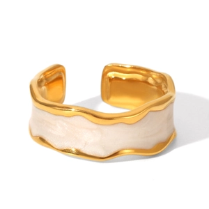 Close-up of irregular wave gold ring with cream enamel drip on polished stainless steel
