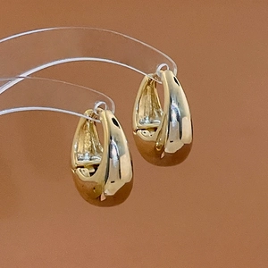 Detailed view of gold-tone U-shaped earrings with high-polish metallic finish